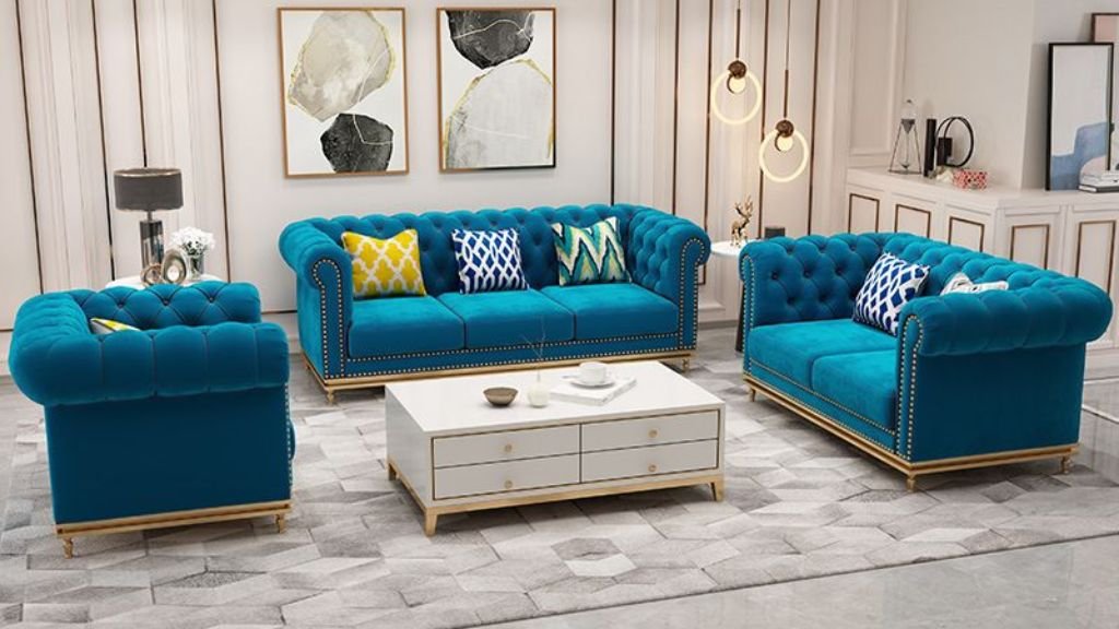 A teal blue Chesterfield sofa set styled with a geometric rug and modern minimalist decor.