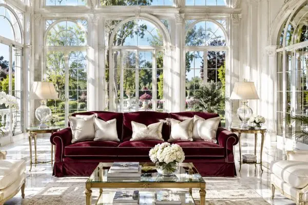 A bright luxury classic glass veranda featuring premium burgundy red seating with cream silk cushions against floor-to-ceiling windows