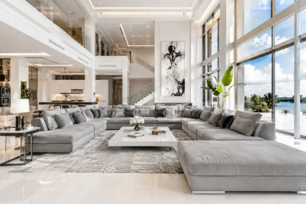 Massive grey U-shaped sectional sofa in a grand luxury living room with high ceilings.