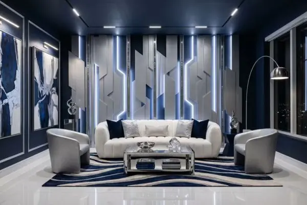 Elegant white curved lounge couch in a deep navy blue and silver maximalist interior room with geometric metal wall plates.