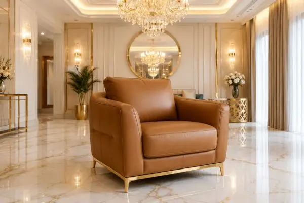 Premium tan caramel leather single sofa with gold legs on a white marble floor.