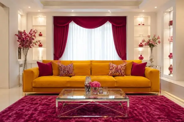 A luxury colorful sofa styled in a bright white and vibrant pink modern living room layout.