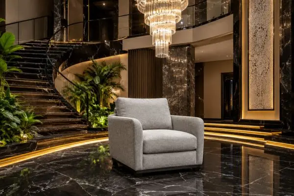 Modern light grey fabric single sofa chair on luxury black marble flooring.