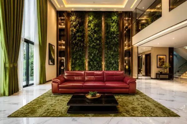 Beautiful modern red leather sofa styled with green curtains and a vertical plant wall.