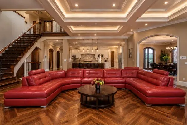 Large red leather sectional sofa in a luxury warm wood home interior.