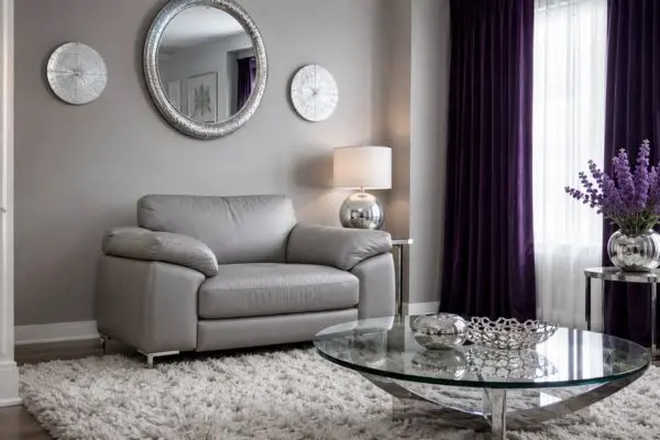 A single compact small leather sofa in a modern grey and purple living room layout.