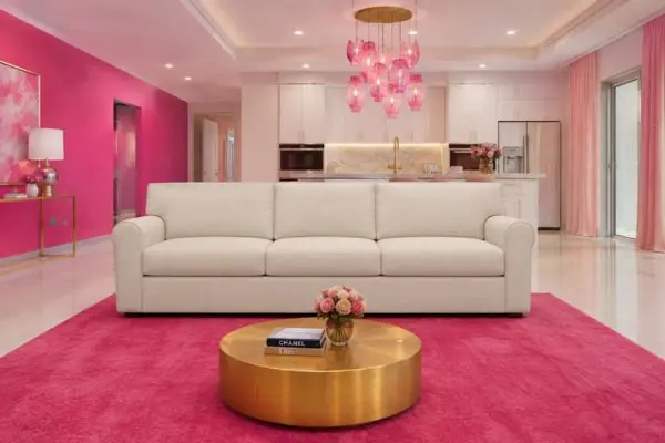 A single cream white couch on a bright magenta rug in a pink luxury apartment.