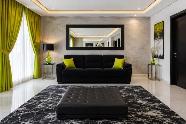 A velvet black Lazy Boy sleeper sofa under a black framed mirror in a lime green decorated room.