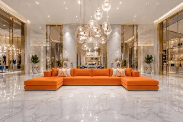 Symmetrical modern orange sectional seating in a luxury white marble lounge.