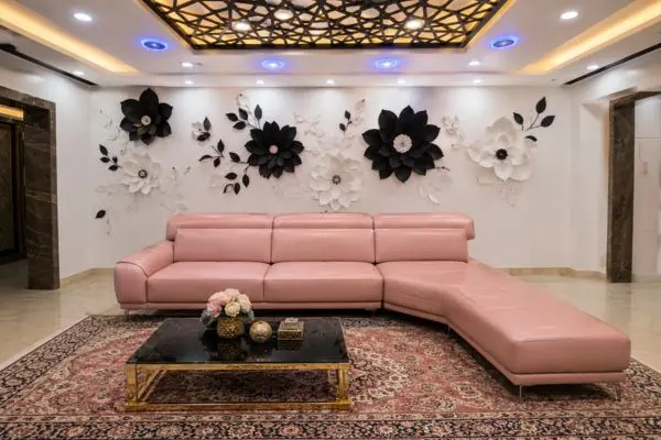 Modern blush pink leather chaise sofa centered in a luxury room with black and white floral wall decor.