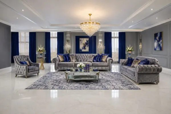 A complete multi-piece grey velvet Ashley sofa set with royal blue pillows in a luxury living room.